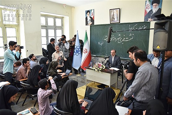 نشست خبری شهردار مشهد پشت میز و نیمکت مدرسه